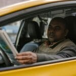 Kierowca taksówki czyta magazyn, czekając na pasażera