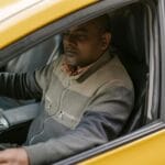 Kierowca taxi czyta gazetę podczas przerwy w zaparkowanym samochodzie