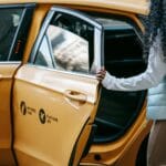 Kobieta z kręconymi włosami wsiada do taksówki w centrum miasta