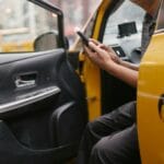 Mężczyzna w taksówce zamawia przejazd przez aplikację w smartfonie