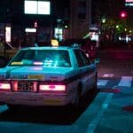 Nocna ulica Tokio z podświetloną taksówką wśród miejskich świateł