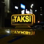 Podświetlony szyld taxi nocą na tle rozmytego miasta