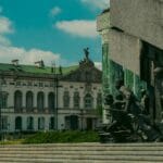 Pomnik Powstania Warszawskiego na tle zabytkowego budynku i błękitnego nieba