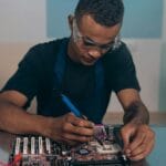 Technik w okularach ochronnych lutuje płytę główną komputera