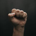 Zaciśnięta pięść uniesiona w górę na ciemnym tle