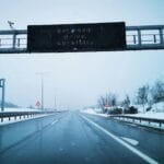 Zasypana śniegiem droga ekspresowa z znakiem ostrzegawczym