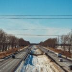 Zimowa droga ekspresowa z autami i ciężarówkami pod błękitnym niebem