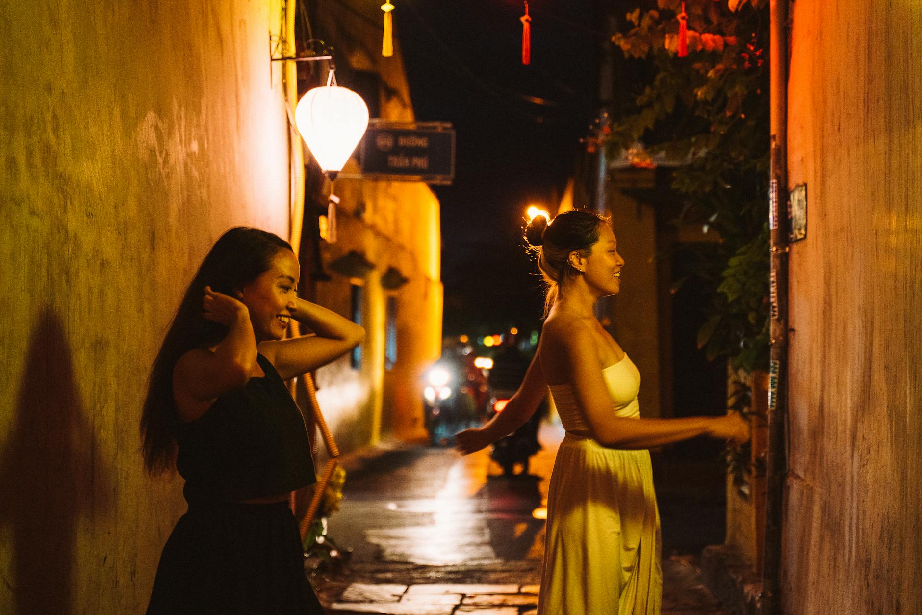 Dwie Azjatki spacerują nocą po ulicy z tradycyjnymi lampionami