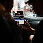 Kierowca i pasażer korzystają z aplikacji taxi w aucie nocą