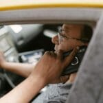 Kierowca taksówki rozmawia przez telefon, jadąc ulicami miasta