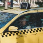 Kierowca żółtej taksówki stoi zaparkowany na ulicy za dnia