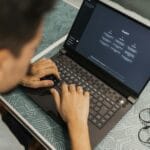 Mężczyzna w okularach pracuje na laptopie z oprogramowaniem AI