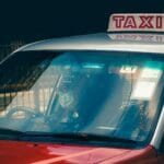 Taksówka w Hongkongu z kierowcą w maseczce czekająca przy ulicy