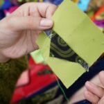 Dłonie zszywające kolorowe kawałki tkanin w narzutę patchworkową