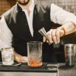 Barman odmierza alkohol jiggerem przy barowym blacie
