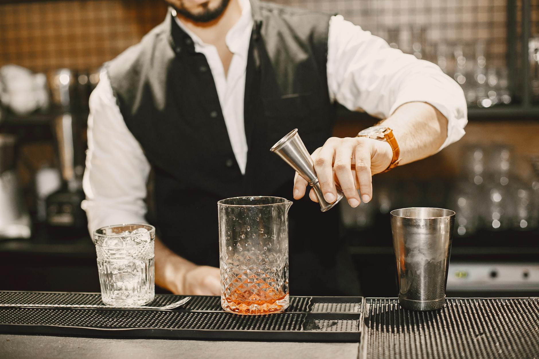 Barman odmierza alkohol jiggerem przy barowym blacie