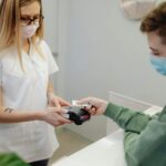 Recepcjonistka w przychodni przyjmuje od pacjenta płatność kartą
