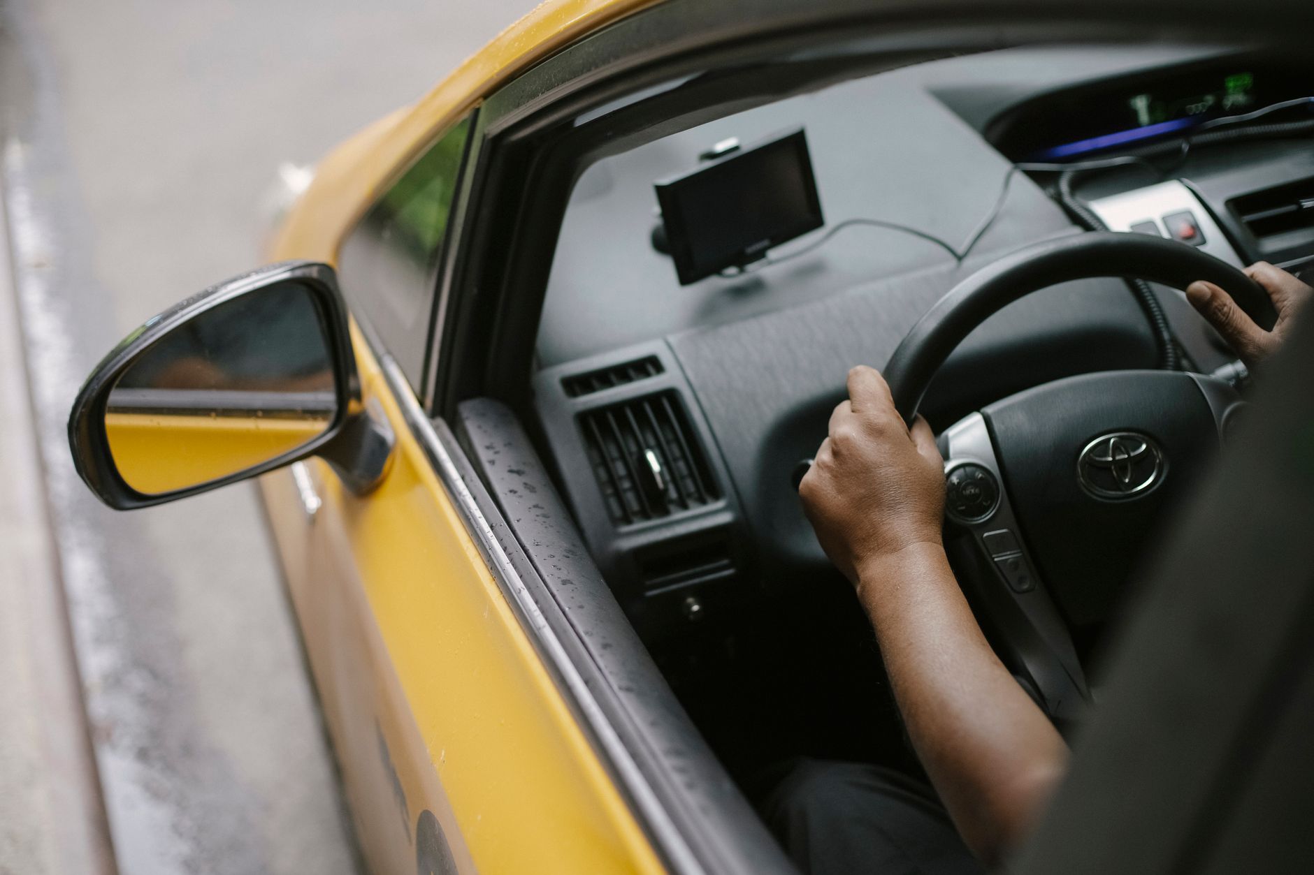 Auto do taxi a wizerunek kierowcy: jak dobór modelu wpływa na opinie, napiwki i powroty klientów Widok z góry na kierowcę prowadzącego żółtą taksówkę z GPS