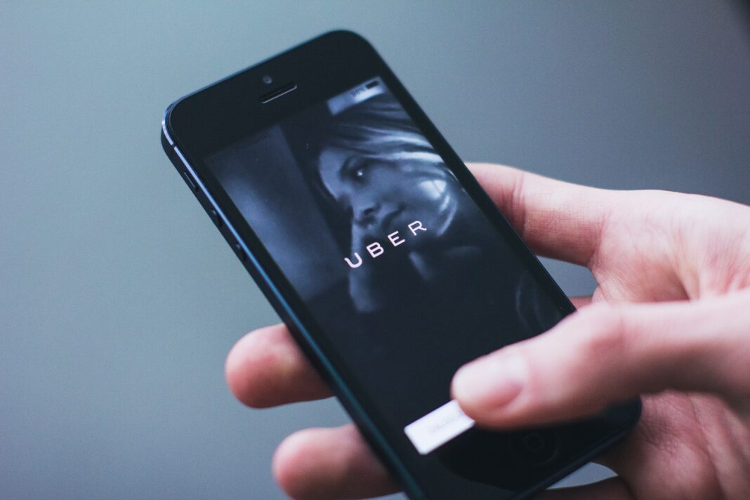 Dłoń trzyma smartfon z otwartą aplikacją Uber Dłoń trzyma smartfon z otwartą aplikacją Uber